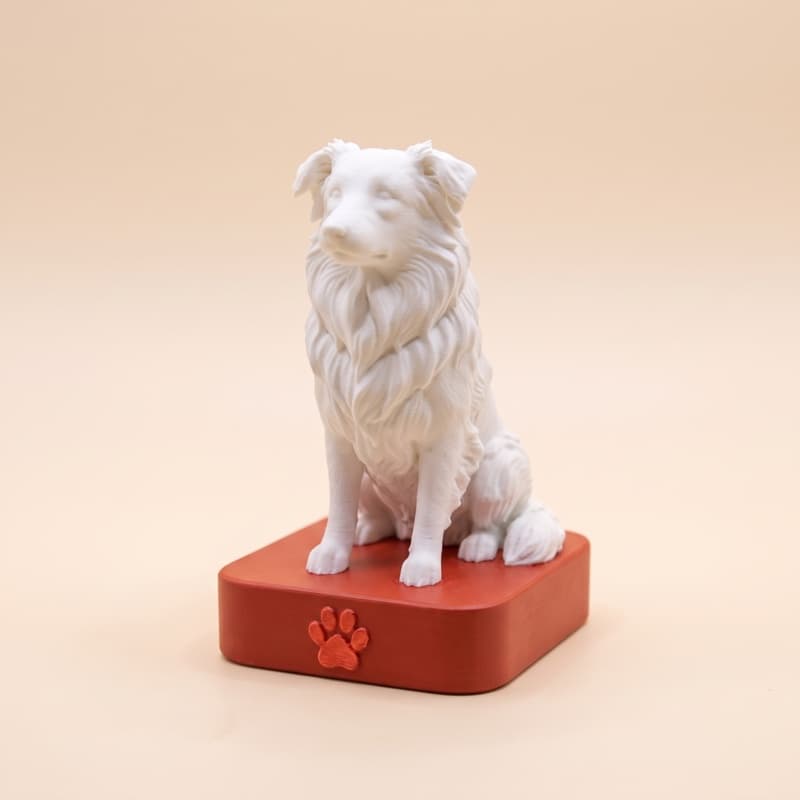 Réplica 3D de un border collie sin pintar sobre una base roja, uno de los colores de base que podés elegir